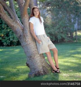 Caucasian Woman Leaning Against A Tree In A Park