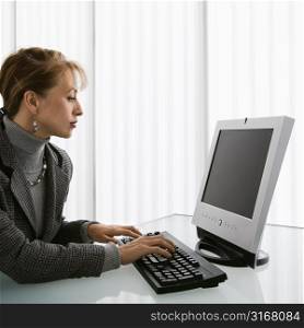 Caucasian woman typing on computer keyboard.