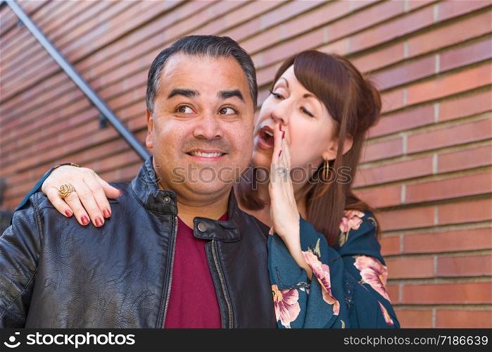 Caucasian Woman Whispering Secret to Hispanic Man.
