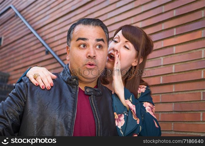 Caucasian Woman Whispering Secret to Hispanic Man.