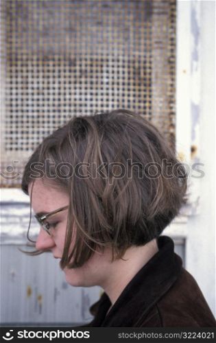 Caucasian Woman With Glasses Sitting In An Industrial Area