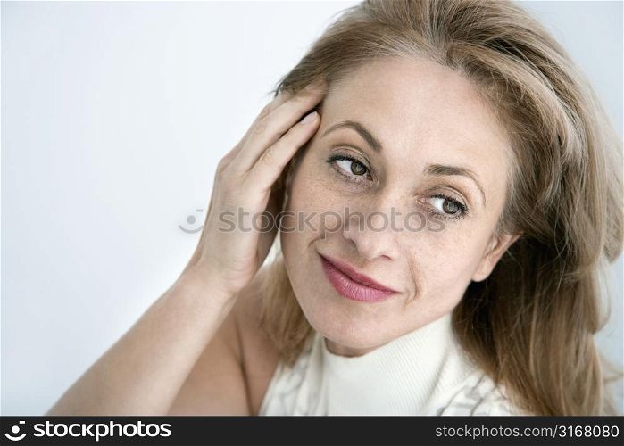 Caucasian woman with hand to head looking away.