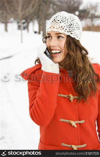Caucasian young adult female holding cell phone outside in snow.