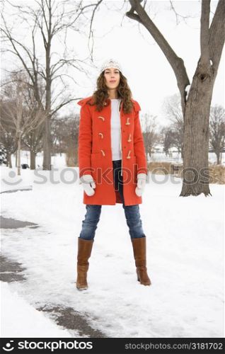 Caucasian young adult female looking at viewer and standing in snow covered street.