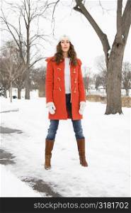 Caucasian young adult female looking at viewer and standing in snow covered street.