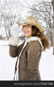 Caucasian young adult female smiling and tilting straw cowboy hat at viewer.
