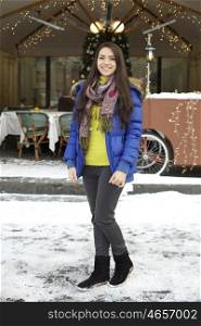 Caucasian young adult female smiling and walking down snow covered street