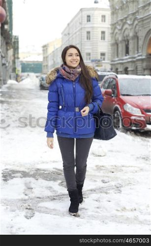 Caucasian young adult female smiling and walking down snow covered street