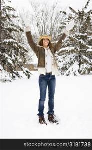 Caucasian young adult female standing and playing in the snow wearing straw cowboy hat.