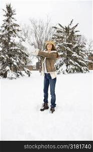 Caucasian young adult female standing throwing a snowball and wearing a straw cowboy hat.