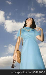 Caucasian young adult woman in retro clothing looking up at sky.