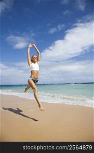 Caucasian young adult woman jumping on beach.