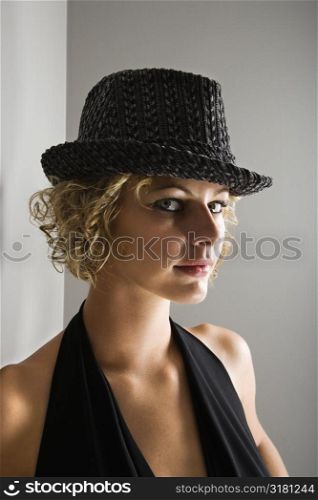 Caucasian young adult woman wearing fedora hat looking at viewer.