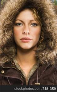 Caucasian young adult woman wearing fur hood looking at viewer.