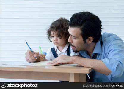 Caucasian young father with beard teaching little cute daughter writing or drawing on book in living room after work. Happy handsome dad help kid learning at home