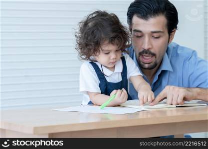 Caucasian young father with beard teaching little cute daughter writing or drawing on book in living room after work. Happy handsome dad help kid learning at home