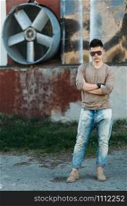 Caucasian young handsome adult male in blue jeans standing in front of a brick wall