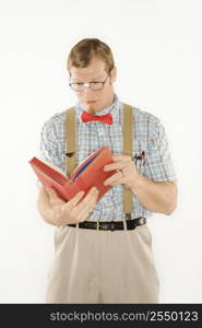 Caucasian young man dressed like nerd reading book.