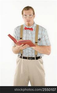Caucasian young man dressed like nerd with book open looking at viewer.