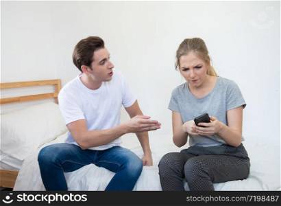 Caucasian young man use smart mobile phone chatting secrecy on bed while his girlfriend sleeping.Cheating boyfriend Secretly use cellphone,lifestyle relationship social problem.. caucasian couple argue with phone on bed at home