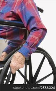 Caucasion male elderly hands gripping wheels of wheelchair.