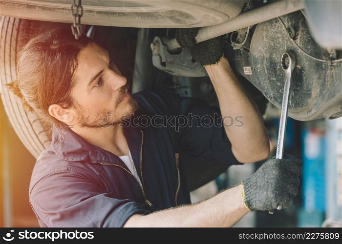 Caucasion male mechanic car service staff worker working in garage fix drive shaft problem
