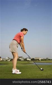 Caucasion mid-adult woman preparing to drive golf ball.