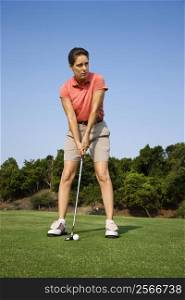 Caucasion mid-adult woman putting golf ball.