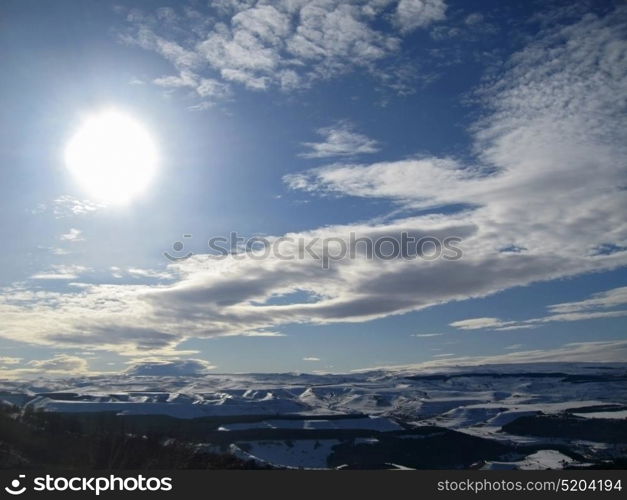 Caucasus mountains under big sun and clouds