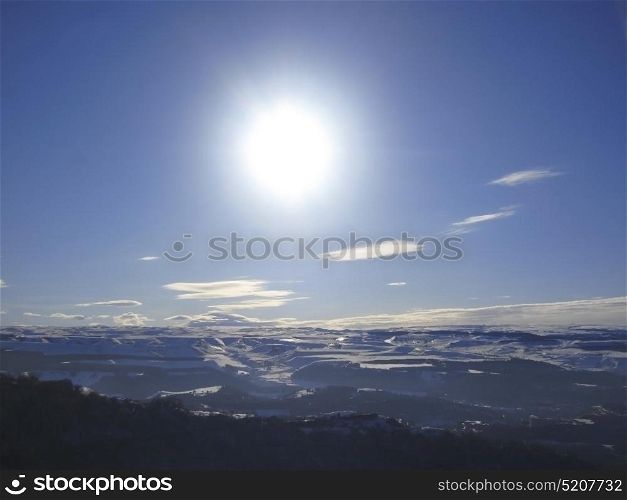 Caucasus mountains under big sun and clouds