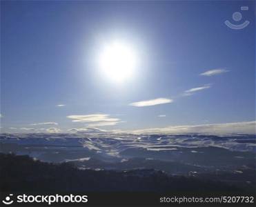 Caucasus mountains under big sun and clouds