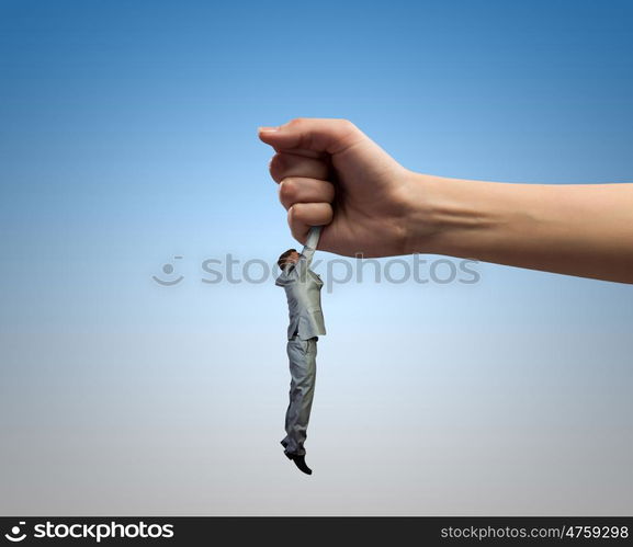 Caught businessman. Close up of human hand holding miniature of businessman