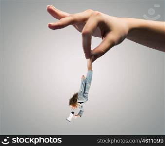 Caught businesswoman. Giant human hand holding miniature of businesswoman