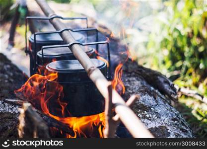 Cauldron boils on the fire, camping in the forest. In marching a saucepan preparing food. Adventure tourism,cooking on a fire. Survival in the forest. Travel concept.
