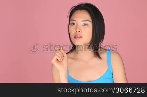 Causal woman pointing at something isolated over a pink background