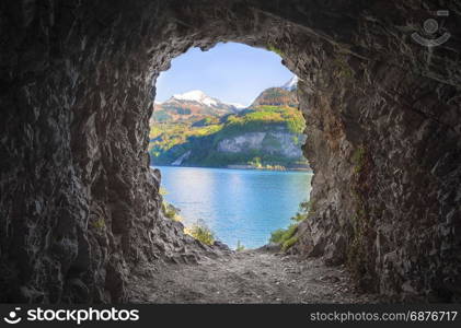 Cavern at the end of a tunnel, with stone walls and a lovely view over the Swiss Alps and the Walensee lake.