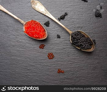 caviar of paddlefish fish and red chum salmon caviar in a spoon, black background, top view