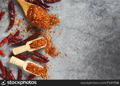 cayenne pepper on wooden spoon spices and dried chilli peppers background / group of red hot chilli powder on black plate top view ingredients table asian food spicy in thailand