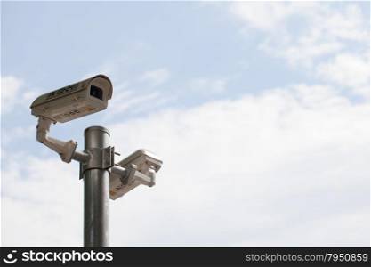 CCTV cameras on poles. Behind the clear sky in the daytime.