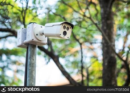 cctv security camera installed a top of round metal pole for surveillance nearby with natural background.
