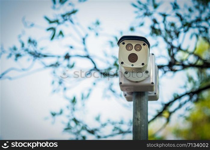 cctv security camera installed a top of round metal pole for surveillance nearby with natural background.