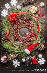 Cedar Christmas wreath with winter berries , ribbon and holiday decorations on rustic wooden background, top view.