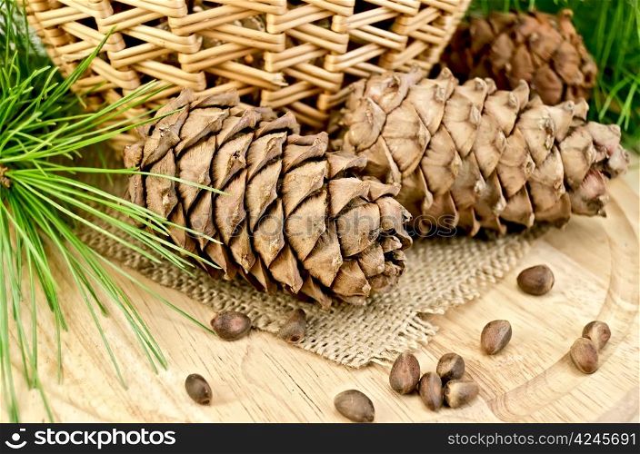 Cedar cones, nuts, green twigs, wicker basket on a background of burlap cloth and wooden board