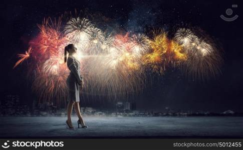 Celebrate your success. Young elegant businesswoman watching fireworks in sky