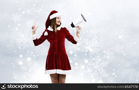 Celebrating New Year. Young attractive Santa girl listening music in headphones