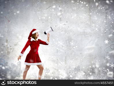 Celebrating New Year. Young attractive Santa girl listening music in headphones