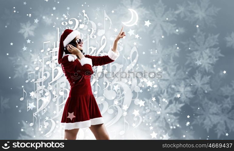 Celebrating New Year. Young attractive Santa girl listening music in headphones