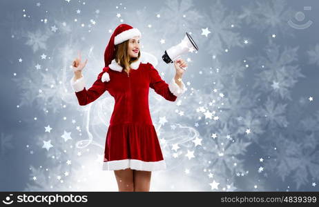 Celebrating New Year. Young attractive Santa girl listening music in headphones