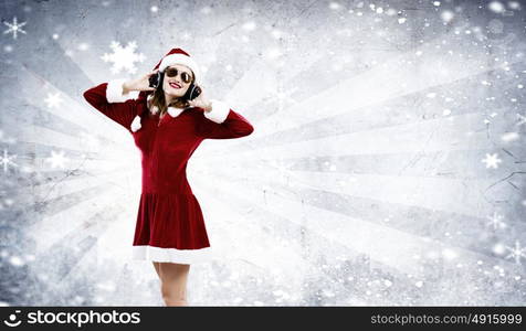 Celebrating New Year. Young attractive Santa girl listening music in headphones