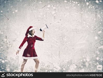 Celebrating New Year. Young attractive Santa girl listening music in headphones